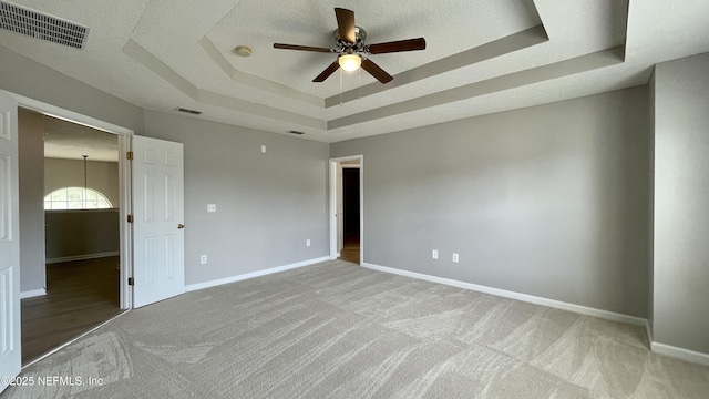 spare room featuring a raised ceiling, visible vents, and baseboards