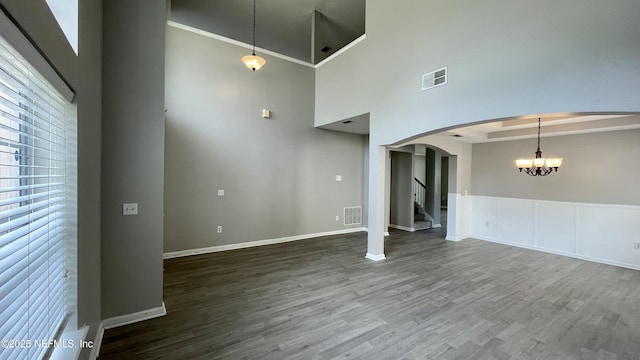 spare room with arched walkways, visible vents, and wood finished floors