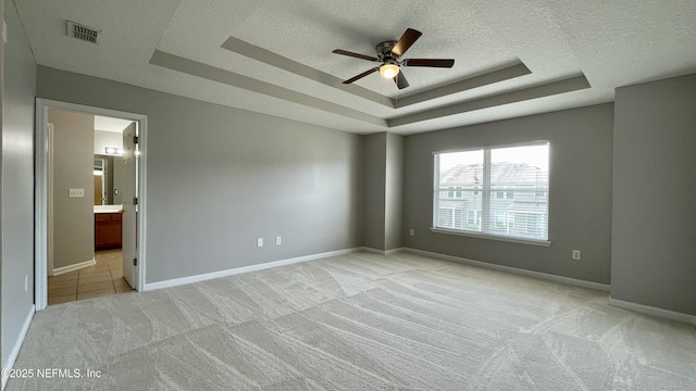 spare room featuring visible vents, a tray ceiling, a textured ceiling, and light colored carpet