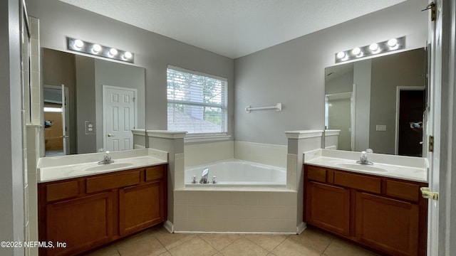 full bathroom with a sink, two vanities, a garden tub, and tile patterned floors