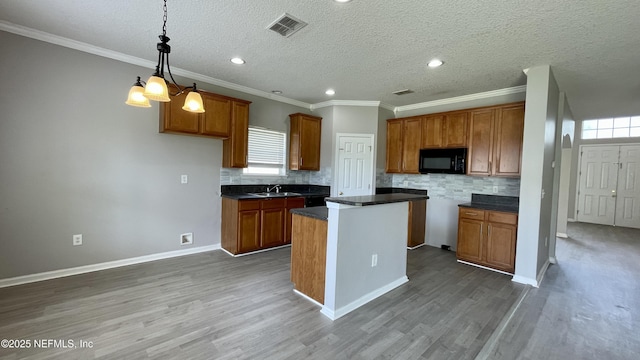 kitchen featuring black microwave, brown cabinets, visible vents, and wood finished floors