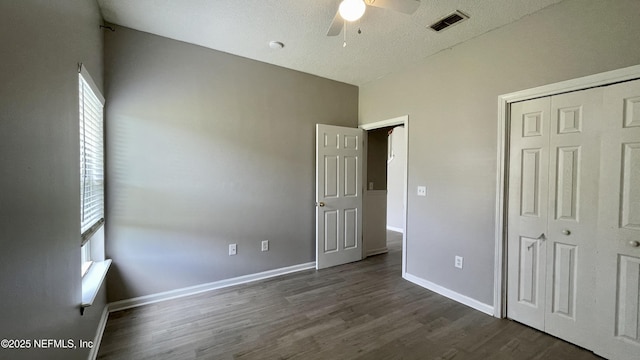 unfurnished bedroom featuring baseboards, visible vents, dark wood finished floors, ceiling fan, and a closet