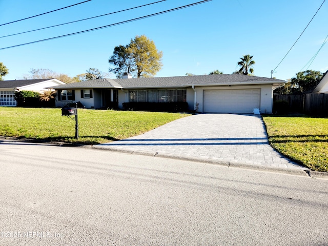 ranch-style house with decorative driveway, a chimney, stucco siding, an attached garage, and a front yard