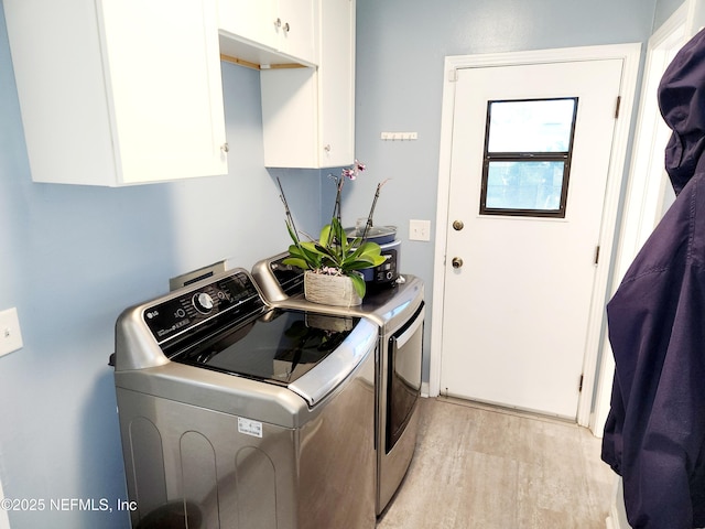 laundry room with cabinet space, light wood-style floors, and washing machine and clothes dryer