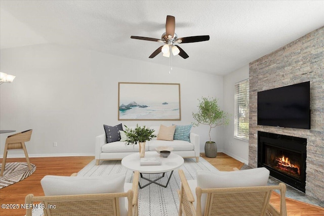 living room featuring a fireplace, a textured ceiling, lofted ceiling, and wood finished floors