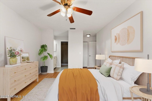 bedroom featuring visible vents, two closets, a ceiling fan, and wood finished floors