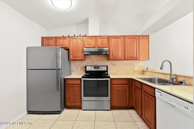 kitchen with a sink, light countertops, vaulted ceiling, under cabinet range hood, and appliances with stainless steel finishes