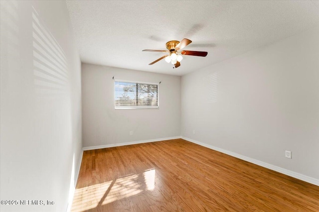 unfurnished room featuring ceiling fan, baseboards, a textured ceiling, and wood finished floors