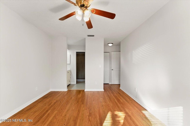 interior space with visible vents, ceiling fan, baseboards, light wood-type flooring, and ensuite bathroom