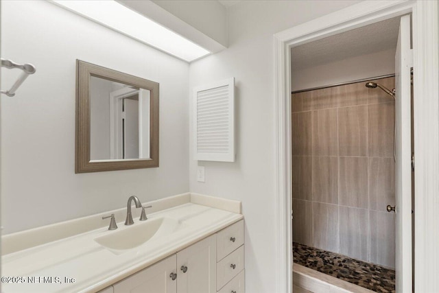 bathroom with tiled shower and vanity