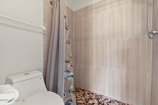 bathroom with toilet and tiled shower