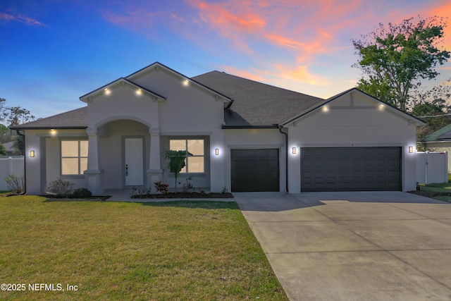 ranch-style house with a garage, fence, a lawn, and stucco siding