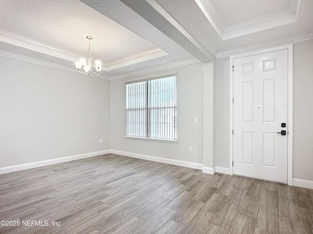 unfurnished room with a notable chandelier, a raised ceiling, ornamental molding, light wood-type flooring, and baseboards