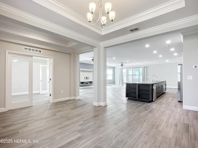 unfurnished living room featuring light wood-style floors, visible vents, a sink, and ceiling fan with notable chandelier