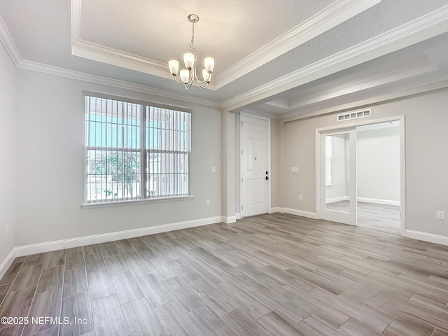 empty room featuring baseboards, a tray ceiling, wood finished floors, and a notable chandelier