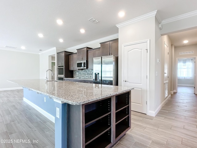 kitchen featuring dark brown cabinetry, tasteful backsplash, a spacious island, stainless steel appliances, and a sink