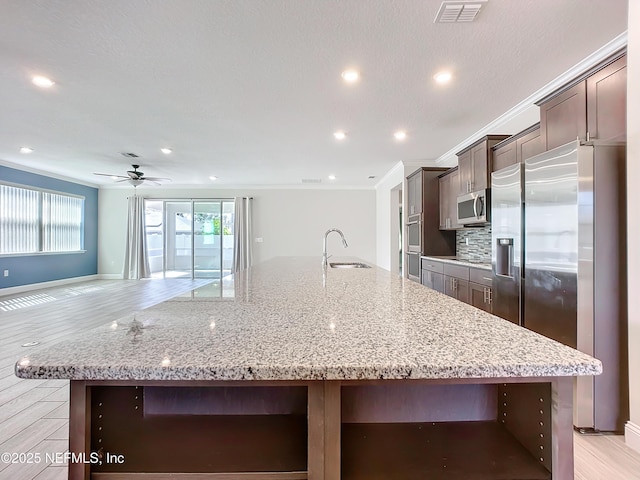 kitchen featuring a spacious island, visible vents, decorative backsplash, appliances with stainless steel finishes, and a sink