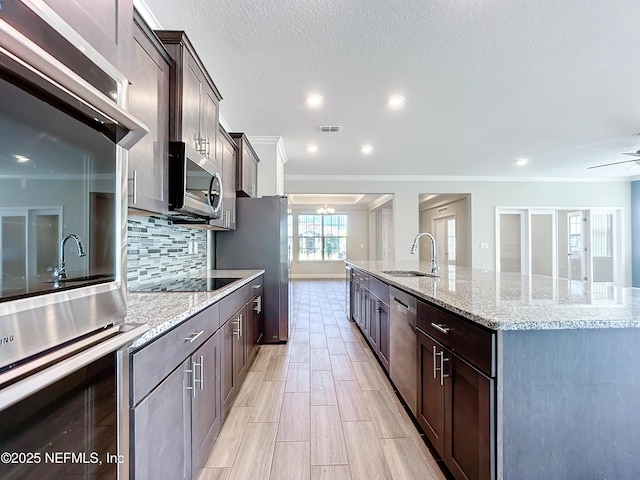 kitchen featuring visible vents, decorative backsplash, a large island, appliances with stainless steel finishes, and a sink