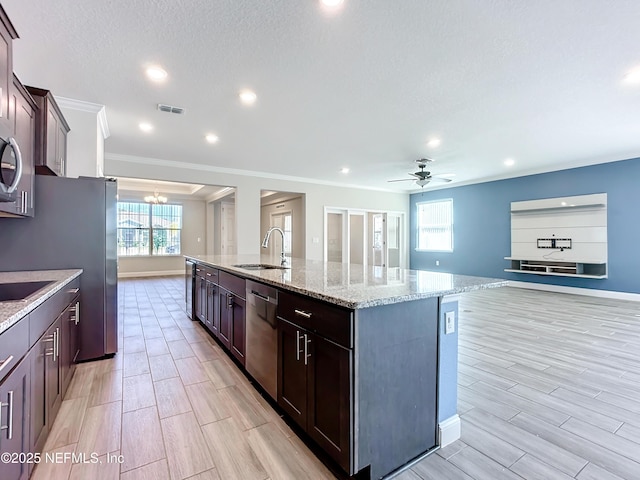 kitchen with stainless steel appliances, wood finish floors, a sink, visible vents, and a center island with sink