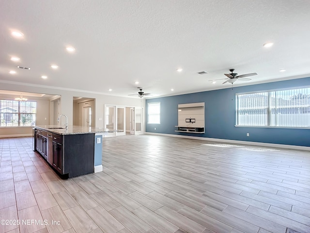 kitchen with a wealth of natural light, a center island with sink, open floor plan, and a sink