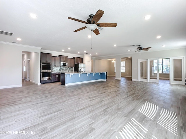 unfurnished living room with ceiling fan, ornamental molding, light wood-type flooring, and visible vents