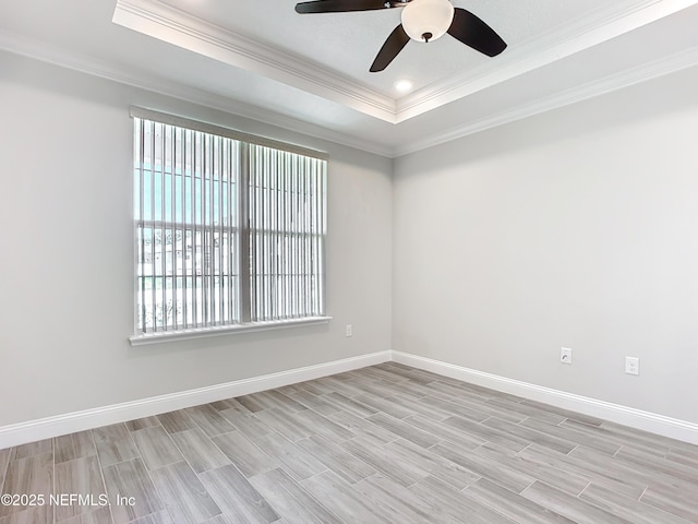 unfurnished room featuring light wood finished floors, baseboards, ornamental molding, and a raised ceiling