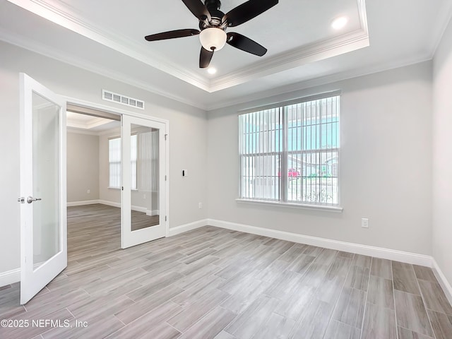 unfurnished room featuring visible vents, baseboards, light wood-style floors, french doors, and a tray ceiling