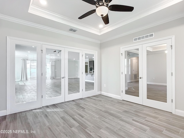 unfurnished sunroom with ceiling fan, visible vents, a raised ceiling, and french doors