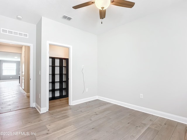 spare room featuring baseboards, visible vents, ceiling fan, and light wood finished floors