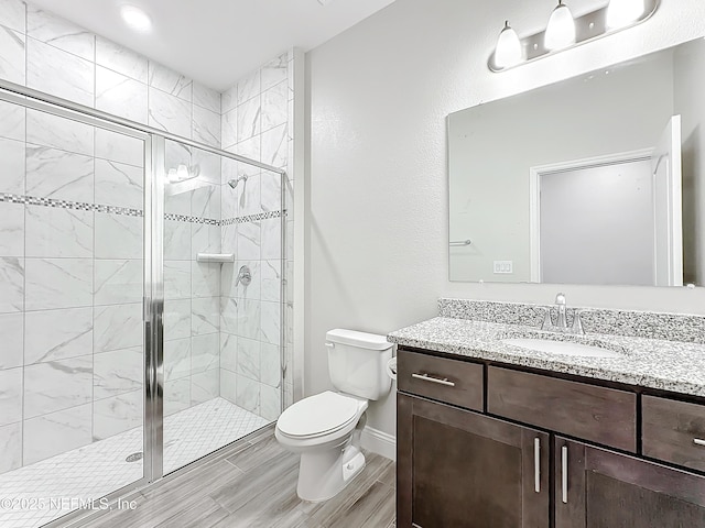 bathroom featuring baseboards, a shower stall, toilet, and vanity