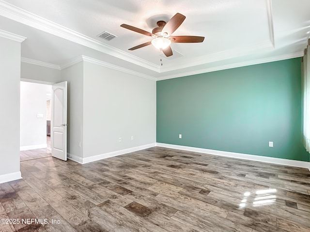 spare room with baseboards, visible vents, a ceiling fan, ornamental molding, and wood finished floors