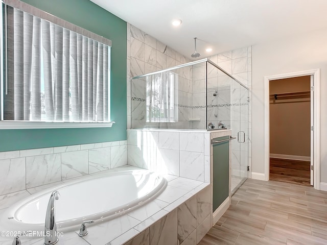 full bath featuring baseboards, a shower stall, a bath, and a walk in closet