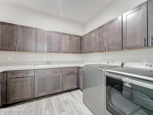 washroom with a sink, cabinet space, and washer and dryer