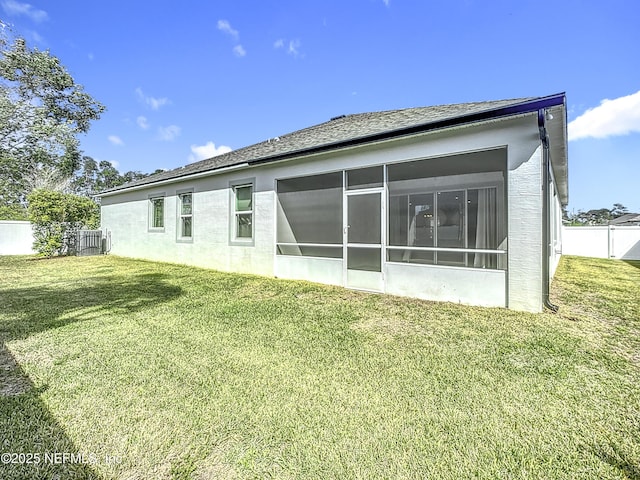 rear view of property featuring a sunroom, fence, and a lawn