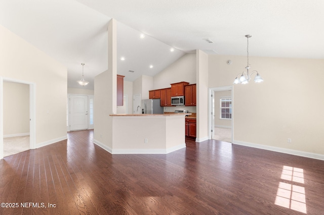 kitchen featuring dark wood-type flooring, open floor plan, appliances with stainless steel finishes, an inviting chandelier, and pendant lighting