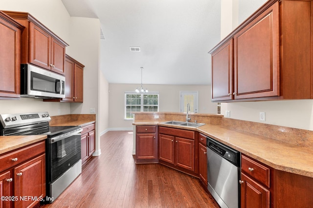 kitchen with a peninsula, a sink, visible vents, appliances with stainless steel finishes, and dark wood finished floors