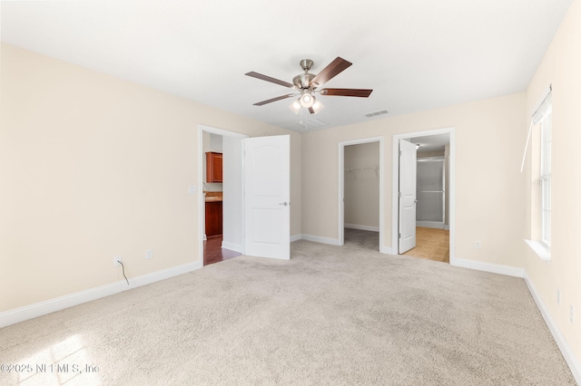 unfurnished bedroom with light carpet, baseboards, a spacious closet, and visible vents