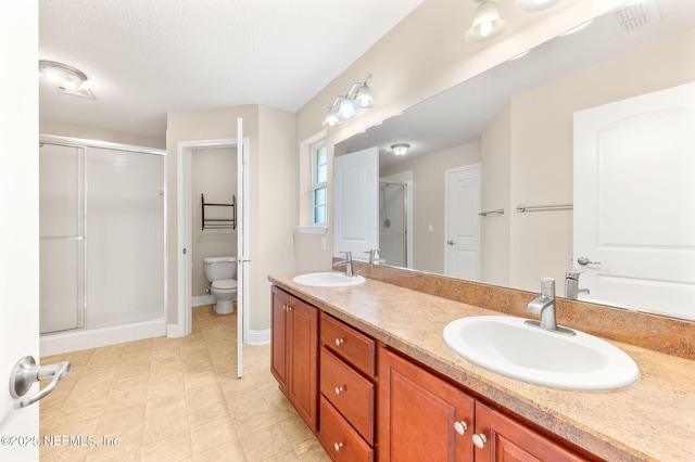 full bath with toilet, a stall shower, double vanity, and a sink