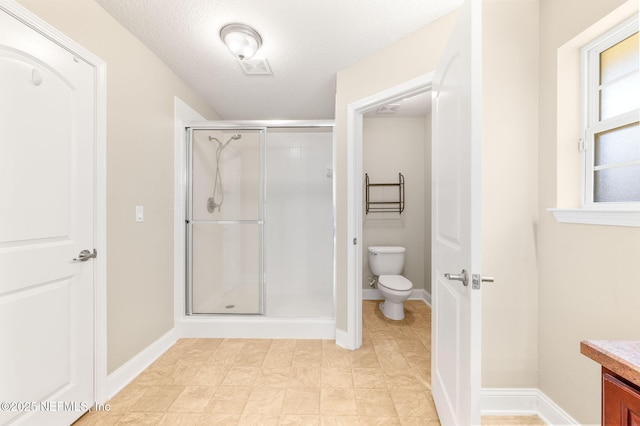 full bathroom featuring a textured ceiling, toilet, vanity, baseboards, and a shower stall