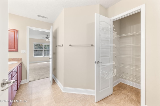 bathroom featuring baseboards, visible vents, a textured ceiling, and vanity