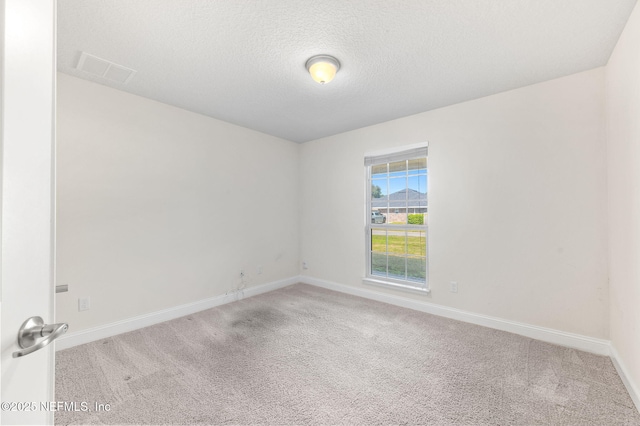 unfurnished room with carpet floors, visible vents, a textured ceiling, and baseboards