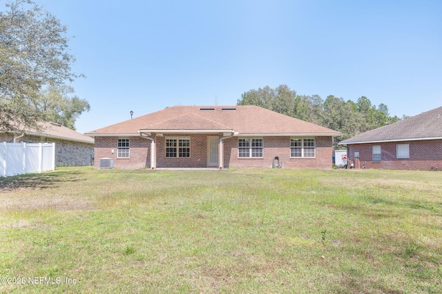 back of house with a shingled roof, fence, a lawn, and brick siding