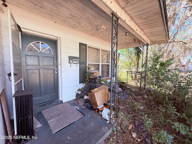 property entrance featuring a porch and concrete block siding