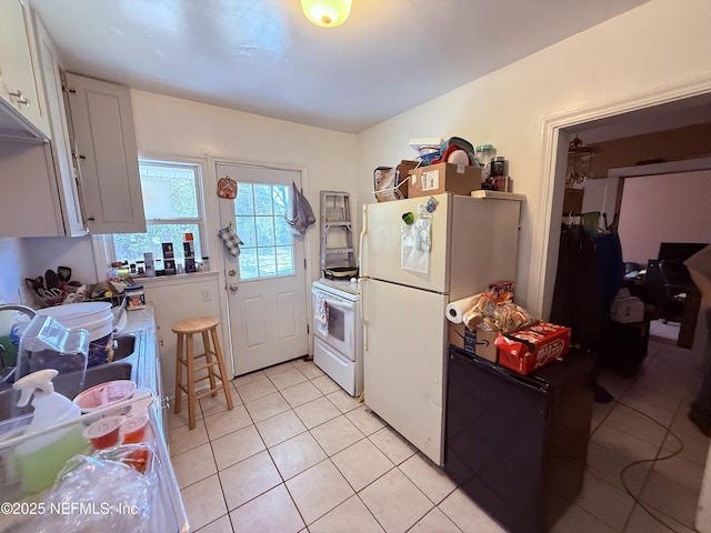 kitchen featuring white appliances, white cabinets, and light tile patterned floors