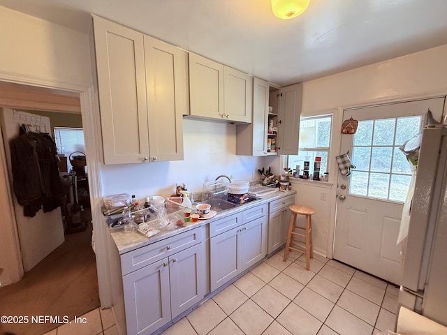 kitchen with gray cabinetry, light countertops, freestanding refrigerator, light tile patterned flooring, and open shelves