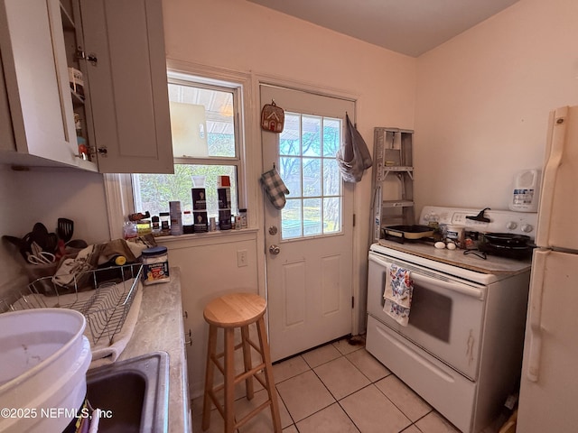 kitchen with light tile patterned floors, white appliances, and light countertops