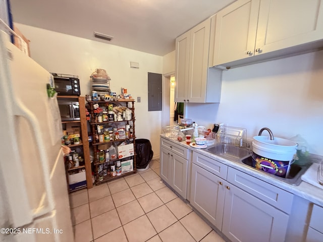 kitchen with visible vents, light countertops, electric panel, freestanding refrigerator, and light tile patterned flooring