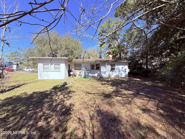 back of property featuring a chimney and a yard