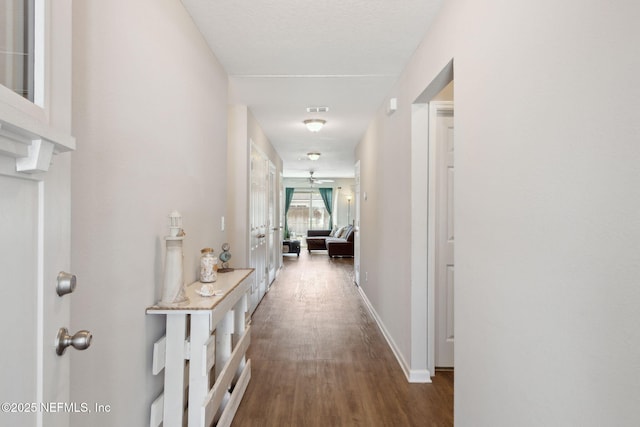 corridor with wood finished floors, visible vents, and baseboards