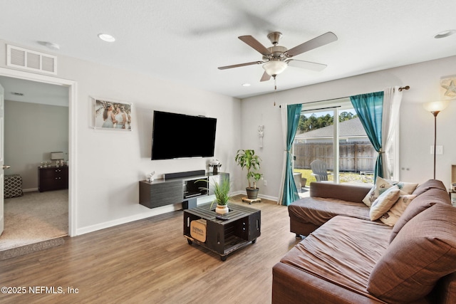 living area with light wood-type flooring, baseboards, visible vents, and ceiling fan